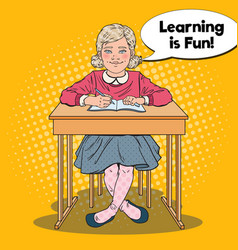 Pop art happy schoolgirl sitting at school desk Pop art happy schoolgirl sitting at school desk vector image