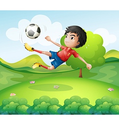 A boy kicking the soccer ball at the hilltop A boy kicking the soccer ball at the hilltop vector image
